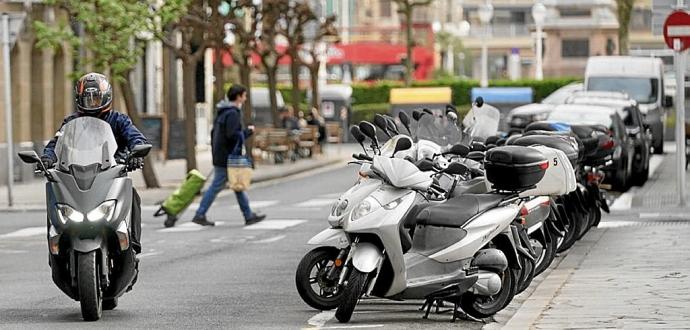 Una moto circulando por el centro de Donostia junto a otras aparcadas.