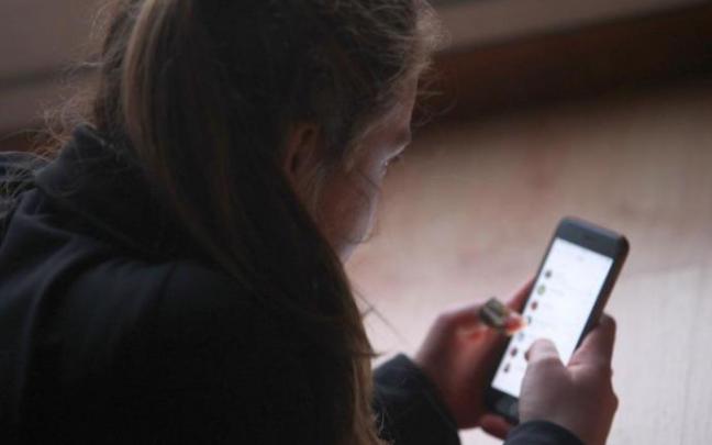 Una adolescente chatea con su móvil