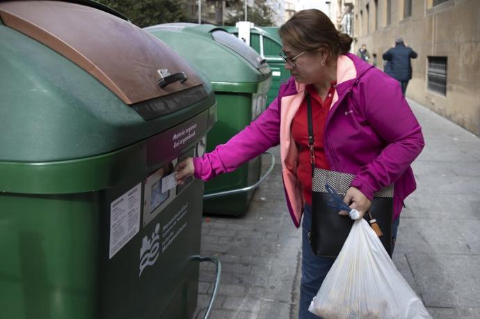 Una mujer abre con la tarjeta un contenedor de orgánica en el Ensanche.