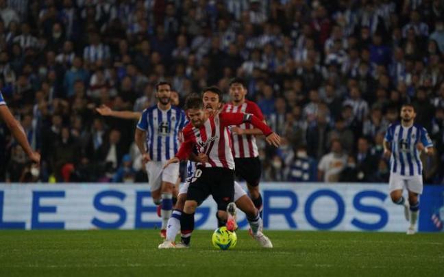 Iker Muniain lucha por hacerse con un balón.