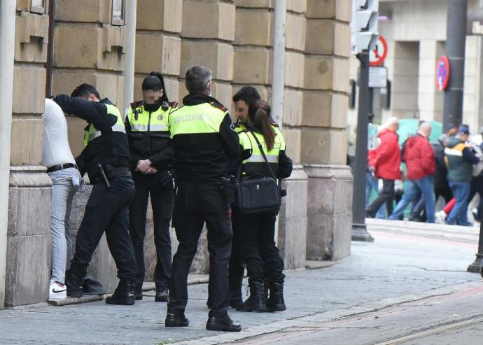 Un agente cachea a un presunto delincuente ante varios compañeros de patrulla.