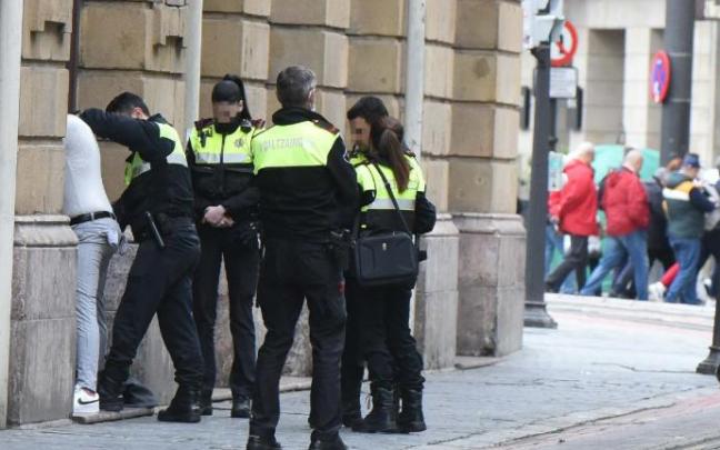 Un agente cachea a un presunto delincuente ante varios compañeros de patrulla.