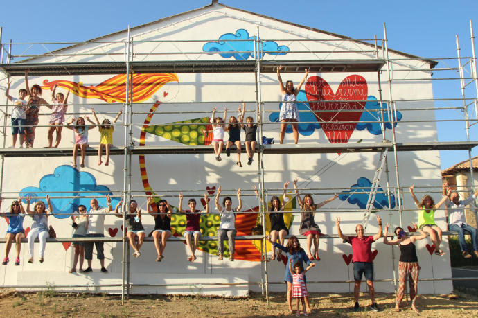 La autora Leire Olkotz posa junto con los participantes frente al mural acabado.