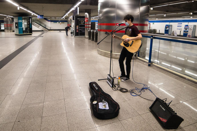 Un músico toca la guitarra en una estación del Metro de Madrid.