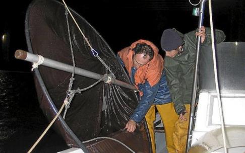 Dos arrantzales vascos pescando angulas desde una embarcación.