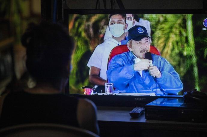Una mujer observa el discurso de Daniel Ortega por televisión