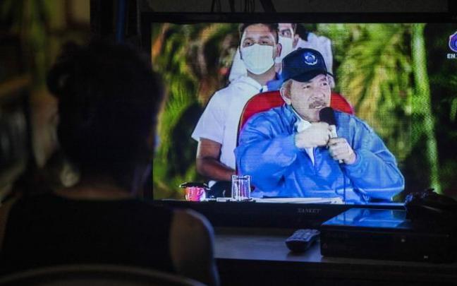 Una mujer observa el discurso de Daniel Ortega por televisión Una mujer observa el discurso de Daniel Ortega por televisión