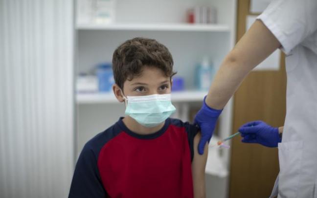 Un sanitario vacuna a un menor Un sanitario vacuna a un menor