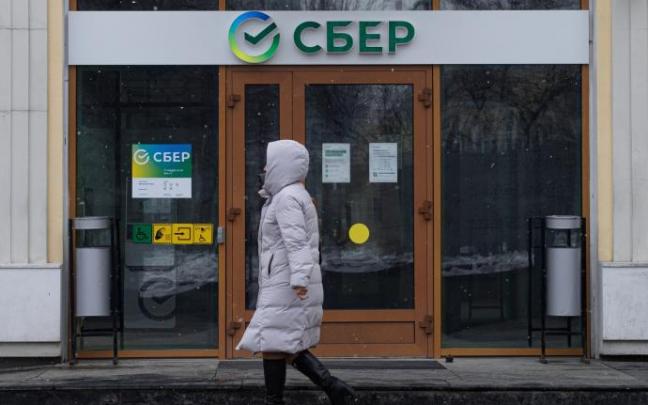 Una mujer camina frente a una oficina de Sberbank
