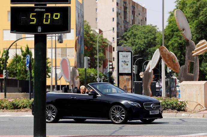 Un coche pasa junto a un termómetro en Murcia que marca los 50 grados.