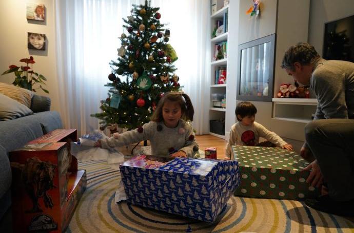 Dos niños desenvolviendo regalos de Navidad.