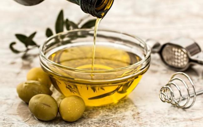 Un bol con aceite de oliva y varias aceitunas.