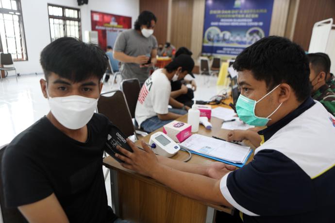 Un joven es examinado antes de recibir una dosis en la vacuna, en Indonesia.