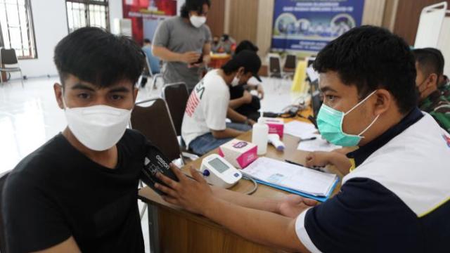 Un joven es examinado antes de recibir una dosis en la vacuna, en Indonesia.