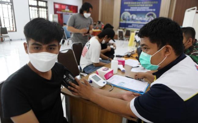 Un joven es examinado antes de recibir una dosis en la vacuna, en Indonesia.