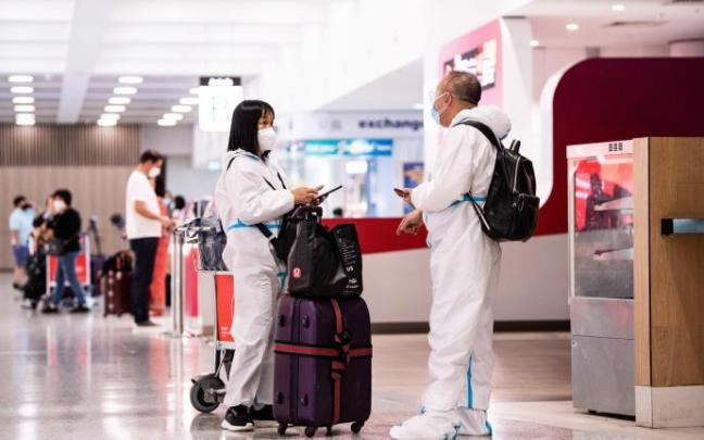 Varias personas con trajes EPI, aeropuerto de Sídney. Varias personas con trajes EPI, aeropuerto de Sídney.