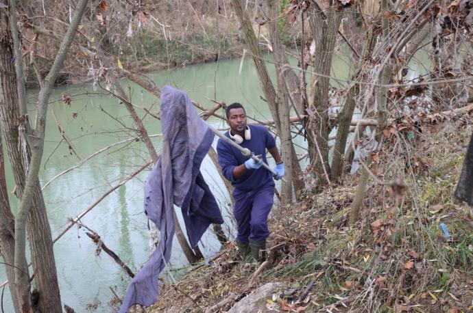 Rachid saca con una pértiga un pantalón que estaba enganchado a la rama de un árbol.