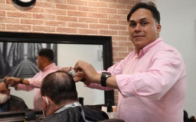 José Ramírez corta el pelo a un cliente en su barbería La Creación, situada en la calle Río Alzania de Azpilagaña.
