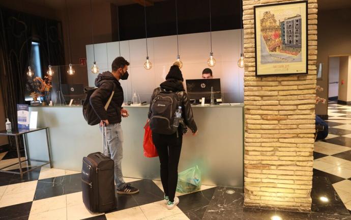 Turistas en el Hotel Pamplona Catedral hacen sus reservas junto al cartel de los últimos Sanfermines, en 2019.