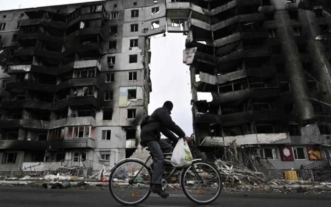 Un hombre pasea en bici junto a un edificio destruido en Borodianka.