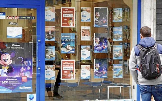 Una persona echa un vistazo a un escaparate de una agencia de viajes de la capital alavesa en el que se pueden ver todas las ofertas que tienen. Entre ellos, el de Eurodisney, en París, uno de los destinos más demandados para cumplir la promesa a los txik