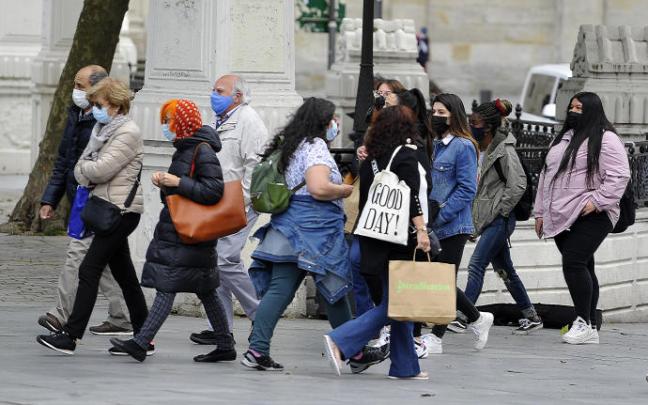 Varias personas pasean protegidas con una mascarilla
