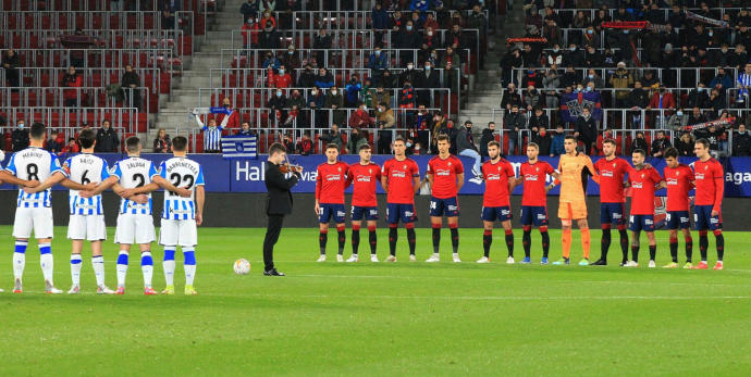 Jugadores de Osasuna y Real Sociedad, abrazados durante el minuto de silencio solo roto por el violín de Mario Oroz.