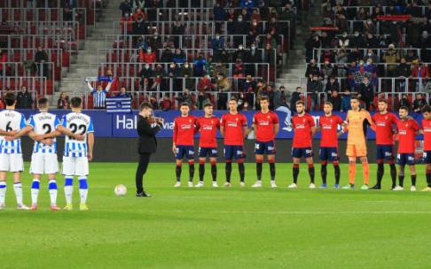 Jugadores de Osasuna y Real Sociedad, abrazados durante el minuto de silencio solo roto por el violín de Mario Oroz.