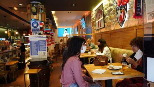 Varias personas toman una consumición sentadas.