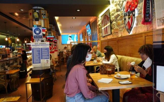 Varias personas toman una consumición sentadas.