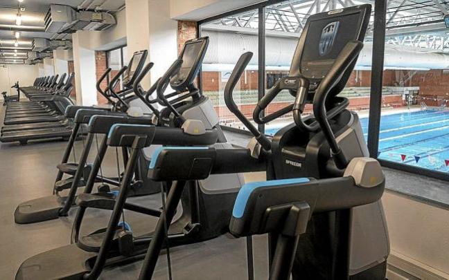 Unas máquinas elípticas junto al ventanal de la piscina.