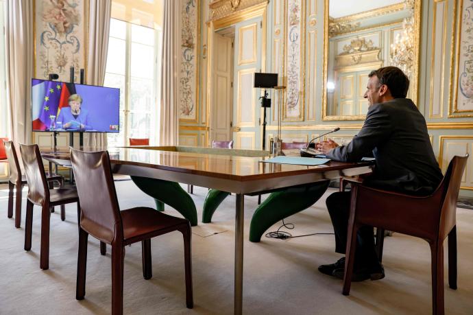 El presidente francés, Emmanuel Macron, habla con la canciller Angela Merkel, durante la conferencia mantenida este lunes entre ambos líderes.