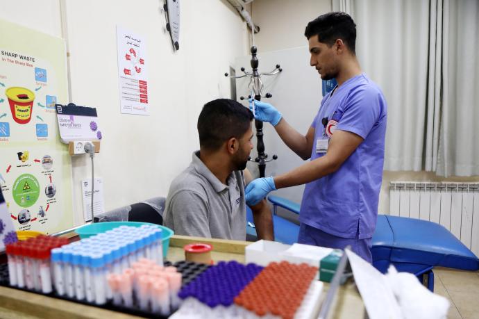 Un trabajador palestino recibe la vacuna en Hebrón.
