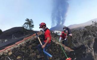 Felipe Murillo y Alain Bravo retiran ceniza de la casa de un palmeño con el volcán de fondo. Felipe Murillo y Alain Bravo retiran ceniza de la casa de un palmeño con el volcán de fondo.