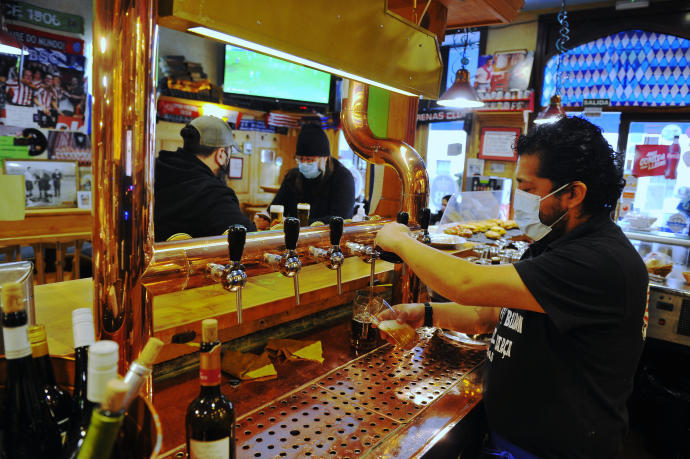 El responsable de un bar sirve a unos clientes.