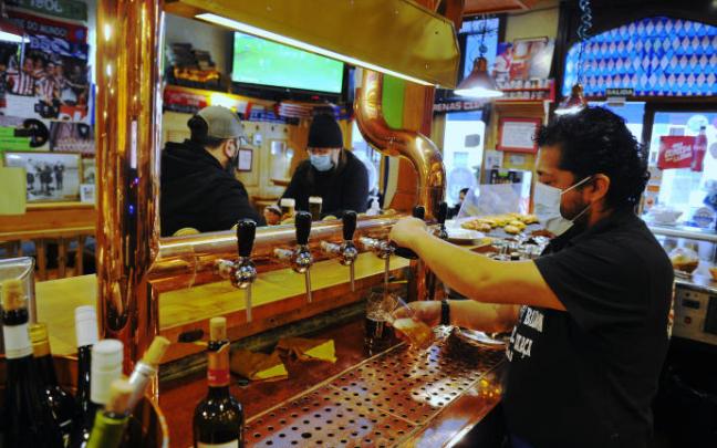 El responsable de un bar sirve a unos clientes.