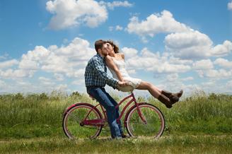 Una pareja de enamorados pasea en bici por el campo.