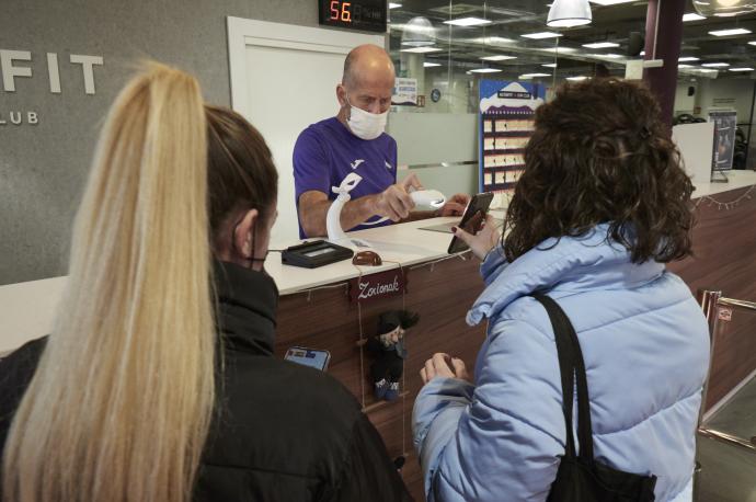 Una joven muestra su pasaporte covid para acceder a un gimnasio.