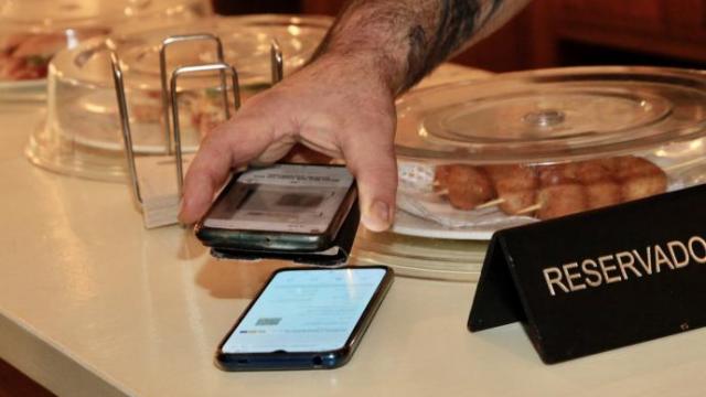 Un cliente enseñando el pasaporte covid para acceder a un bar.