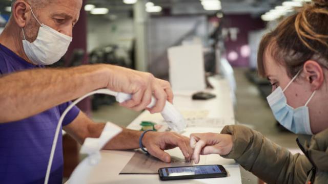 Un trabajador escanea el pasaporte covid de una mujer.