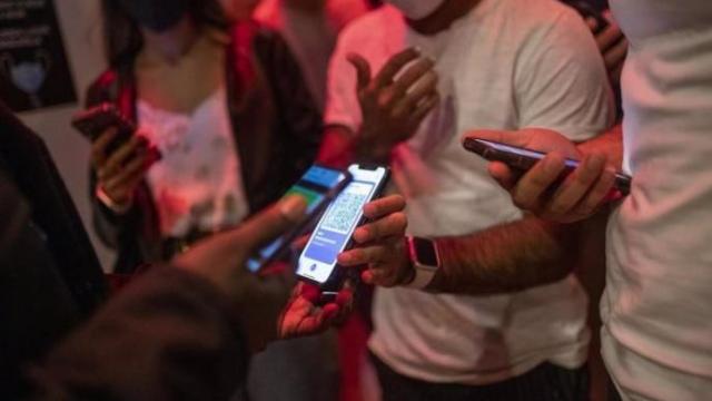 Varias personas muestran su pasaporte covid a la entrada de un local
