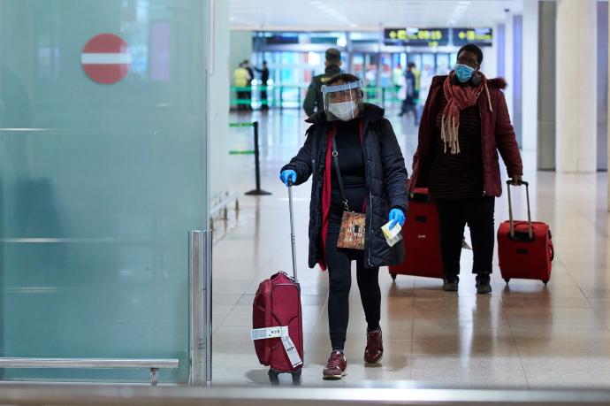 Una viajera con mascarilla y pantalla protectora frente al coronavirus, a su llegada al aeropuerto de El Prat.