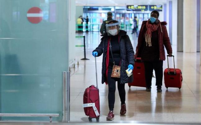 Una viajera con mascarilla y pantalla protectora frente al coronavirus, a su llegada al aeropuerto de El Prat. Una viajera con mascarilla y pantalla protectora frente al coronavirus, a su llegada al aeropuerto de El Prat.