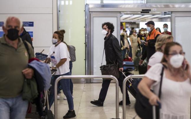 Varios turistas con mascarilla en el aeropuerto.