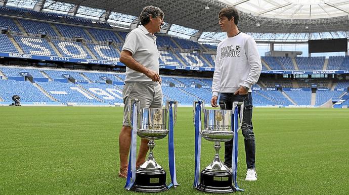 Agustín Gajate y Aritz Elustondo dialogan amistosamente sobre el verde del Estadio de Anoeta con las dos Copas como protagonistas.