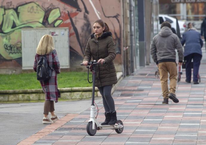 Una joven , ajena a la información, circula a bordo de su patinete por una acera de Vitoria.