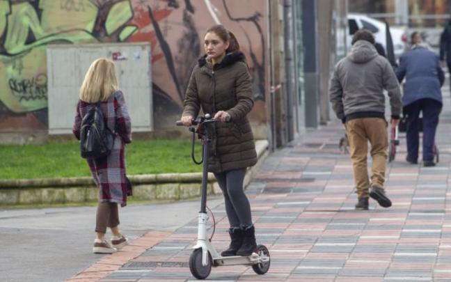 Una joven , ajena a la información, circula a bordo de su patinete por una acera de Vitoria.