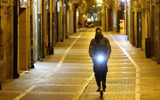 Un joven circula de noche con un patinete eléctrico. Un joven circula de noche con un patinete eléctrico.