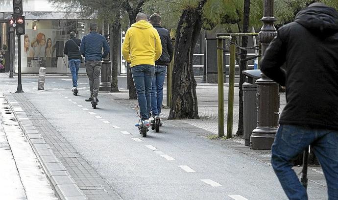 Varias personas en patinete eléctrico, por un bidegorri.