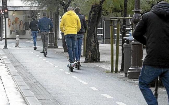 Varias personas en patinete eléctrico, por un bidegorri.